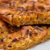 Die goldbraun ausgebackene, mit karamellisierten Zwiebeln belegte Roggenfocaccia zeigt sich im Anschnitt saftig und locker.