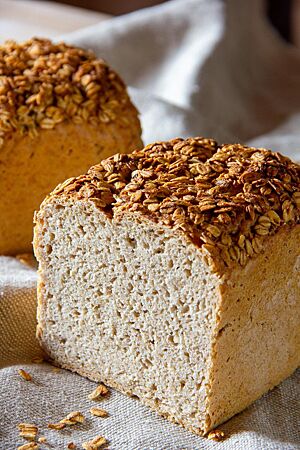 Das Roggenmischbrot im Anschnitt zeigt die lockere, elastische Krume und die goldbraun ausgebackene, mit Haferflocken bestreute Kruste.