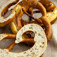 Eine längs halbierte Laugenbrezel zeigt die helle, unregelmäßige Porung unter der dunkelbraunen Kruste.