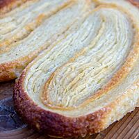 Das fertig gebackene Schweinsohr ist nicht mehr schmal, sondern hat sich breit aufgefächert. Die einzelnen Schichten sind gut erkennbar.