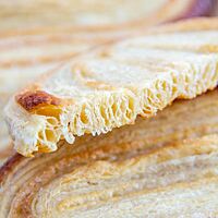 Ein durchgeschnittenes Schweinsohr zeigt die vielen, dünnen Schichten des hellbraun gebackenen Gebäcks.