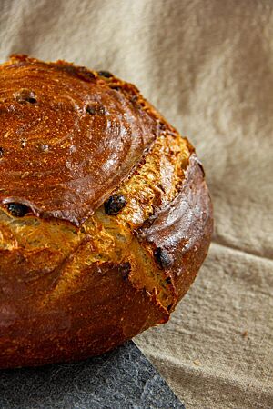 Das runde Fenchelbrot mit glänzender Oberfläche liegt auf der Arbeitsfläche.