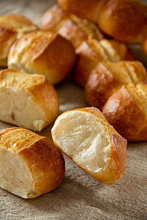 Ein an der Kontaktstelle auseinandergebrochenes Weizenbrötchen der Semmellänge zeigt die weiche, wattige Krume und die knusprige Kruste.
