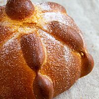Das goldbraun ausgebackene, mit Zucker bestreute Pan de Muerto liegt auf einem Leinentuch.