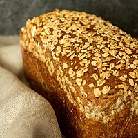 Das braune Roggenbrot in Form eines Kastenbrotes liegt in einem Leinentuch.