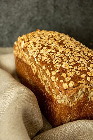 Das braune Roggenbrot in Form eines Kastenbrotes liegt in einem Leinentuch.