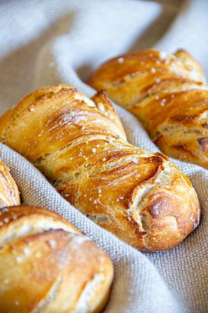 Drei goldgelbe Dinkelbrötchen mit rustikalem Ausbund sind mit weißem Fleur de Sel bestreut.