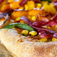 Die Pizza hat einen hellbraun ausgebacken, glatten Rand und ist üppig belegt.