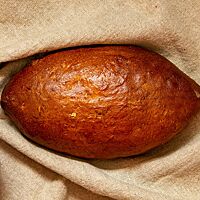 Das kräftig ausgebackene Apfelbrot mit glänzender Kruste liegt in einem Leinentuch.