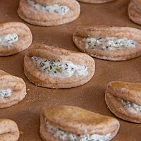 Die ungebackenen, kreisförmigen Teiglinge wurden über der Füllung aus Ziegenfrischkäse, Dill und Parmesan zusammengeklappt.