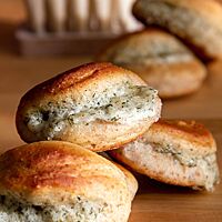 Auf der zugeklappten Seite der ausgebackenen Teigmuscheln schaut die Füllung aus Ziegenkäse, Dill und Parmesan heraus.