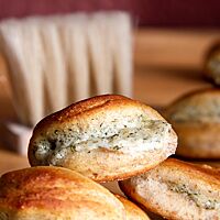 Auf der Oberfläche sind die ausgebackenen Teigmuscheln gebräunt. An der heller gefärbten Seite schaut die Füllung aus Ziegenkäse, Dill und Parmesan heraus.