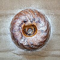 Der Heidelbeer-Biskuit in Form eines Gugelhupfes hat eine goldbraune, mit Puderzucker bestäubte Kruste.