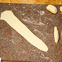 Der Teigling wird zu einem ca. 50 cm langen Band ausgerollt, das an einem Ende spitz zuläuft.