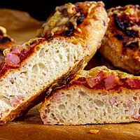 Das Pizzabrötchen mit lockerer, elastischer Krume ist belegt mit Tomatenmark, Kochschinken und zerlaufenem Käse.