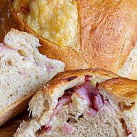 Im Anschnitt zeigt sich das Handbrot mit lockerer und elastischer Krumenstruktur sowie einer Füllung aus Kochschinken und Käse.