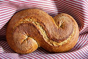 Der als „S“ geformte und der Länge nach eingeschnittene Laib des Senflings liegt in einem gestreiften Tuch.