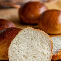 Ein Milchbrötchen im Anschnitt zeigt die feinporige, fluffige Krumenstruktur umgeben von einer dünnen Kruste.
