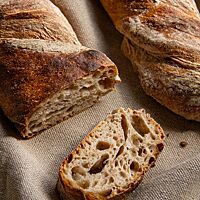 Das kräftig ausgebackene, leicht bemehlte Wurzelbrot mit Roggenschrot zeigt im Anschnitt die offenporige, luftige Krume.