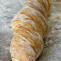 Das in sich verdrehte, leicht bemehlte Wurzelbrot ist goldbraun ausgebacken.