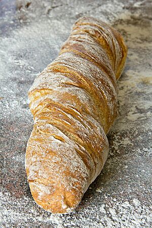 Das in sich verdrehte, leicht bemehlte Wurzelbrot ist goldbraun ausgebacken.