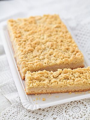 Zwischen Hefeteigboden und üppiger, goldgelb ausgebackener Streuselschicht ist die Puddingfüllung zu sehen.