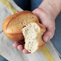 Ein auseinandergebrochenes Milchbrötchen zeigt die lockere, weiche Krume und die goldgelb ausgebackene Kruste.