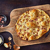 Ein Flammkuchen, klassisch belegt mit Schmand, Speck und Zwiebeln.