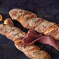 Die Kruste des stangenförmigen Brotes ist herrlich knusprig und voller Aromen, die Krume locker und elastisch mit einer groben Porung.