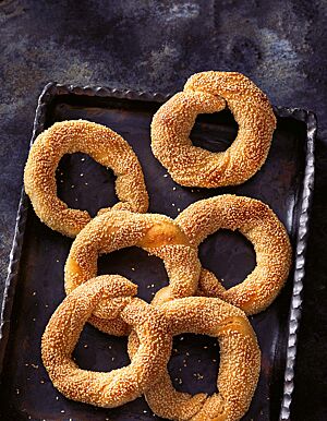 Die gedrehten Sesamringe sind goldbraun ausgebacken und liegen auf einer dunklen Platte.