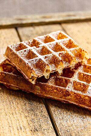 Die goldbraun ausgebackene, mit Puderzucker bestreute Waffeln hat eine lockere, weiche Krume.