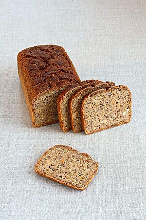 Das goldbraun ausgebackene Sportbrot mit glatter Kruste zeigt im Anschnitt Hirsekörner, Karotten und Mandeln in der lockeren, kleinporigen Krume.