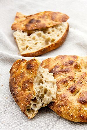 Das mit Sesam bestreute, goldbraun ausgebackene Fladenbrot hat eine grobe, unregelmäßige Porung.