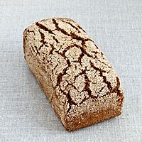 Die Oberfläche des in feinem Roggenschrot gewälzten Pumpernickels weist Risse auf.