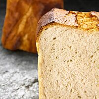 Mehrere Scheiben des Weizenkastenbrotes in der Basisvariante zeigen die helle, klein- bis feinporige Krume und die dünne, hellbraun ausgebackene Kruste.