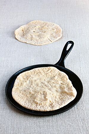 Das hellgelb ausgebackene Naan-Brot liegt in einer Gusseisenpfanne.