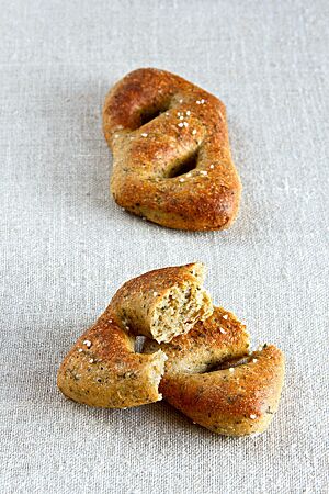Ein auseinandergebrochenes Sommerbrötchen zeigt Kräuter in der gelblich gefärbten, kleinporigen Krume.