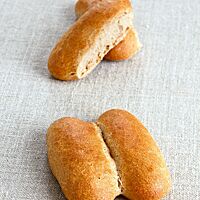 Die paarweise aneinandergebackenen länglichen Dinkelbrötchen sind goldgelb ausgebacken.