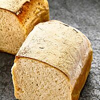 Ein halbiertes Dinkelkastenbrot in der Sauerteigvariante zeigt die weiche, kleinporige Krume.
