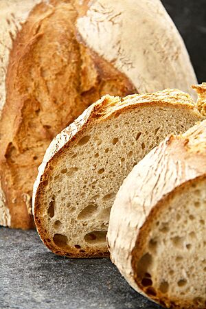 Das Dinkelmischbrot hat eine rustikal aufgerissene Kruste und eine kleinporige Krume mit vereinzelten mittleren Poren.