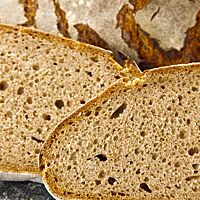 Zwei Scheiben des reinen Roggensauerteigbrotes zeigen die lockere, elastische Krume.