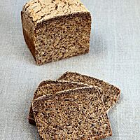 Drei Scheiben des Schwarzbrotes zeigen die dunkelbraun gefärbte, kleinporige Krume.