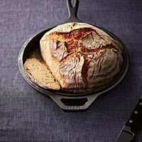 Die kräftig ausgebackene, bemehlte Kruste des runden Kartoffelbrotes ist rustikal aufgerissen.