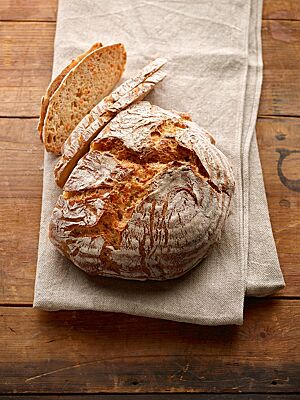 Der knusprige, aufgerissene Laib des Möhrenbrotes hat eine fluffige Krume mit deutlich sichtbaren Möhrenstückchen.