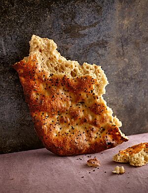 Das kräftig ausgebackene Dinkelfladenbrot mit grobporiger Krume ist auf der Oberfläche mit schwarzem Sesam bestreut.