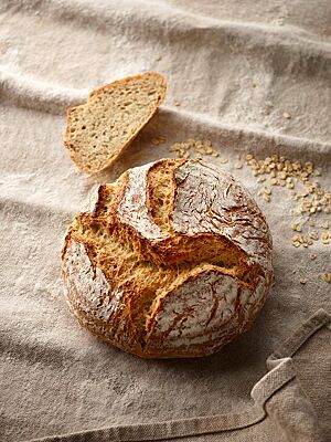Der runde Brotlaib hat eine rustikal aufgerissene Kruste und eine kleinporige, helle Krume.