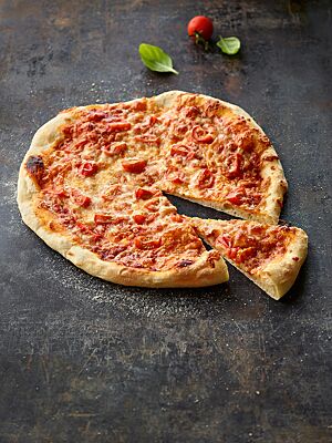 Die knusprig ausgebackene Pizza mit mitteldickem Boden ist mit Tomatenstücken und Mozzarella belegt.