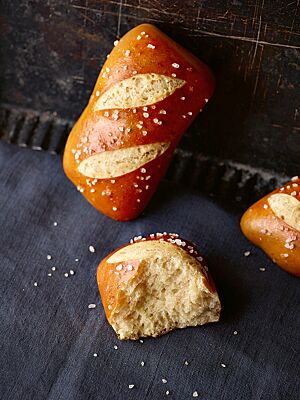 Die eckig geformten Laugenbrötchen haben eine glänzende Kruste mit zwei diagonalen Einschnitten und sind mit grobem Salz bestreut.