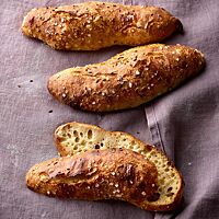 Die länglich und unregelmäßig geformten Dinkelseelen haben eine mit Kümmel und grobem Salz bestreute Kruste und eine helle, mittelporige Krume.