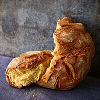 Die kräftig ausgebackene, rustikal aufgerissene Brioche mit dicker, leicht bemehlter Kruste hat eine goldgelbe, mittelporige Krume.